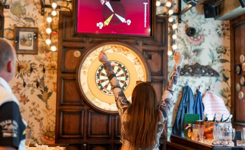 Person cheering in front of dart board